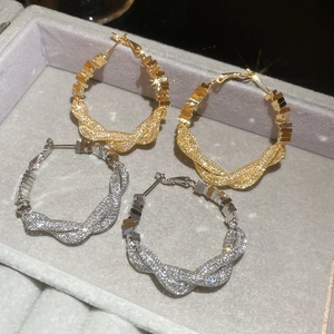 Detail of twisted hoop earrings in gold and silver finish with sparkling starlight texture
