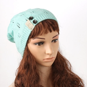 Close-up of mint green knitted beanie with leaf pattern and buttons on mannequin head