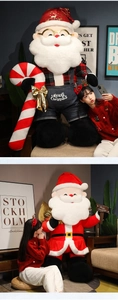 Close-up of giant Santa Claus plush doll featuring red plaid shirt and denim overalls