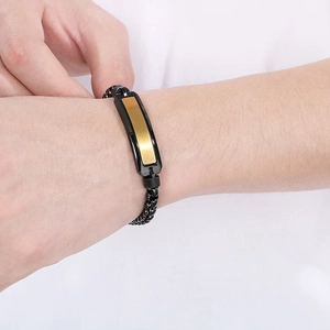 Detail eines schwarzen Titanstahl-Armbands für Herren mit gold-schwarzer Metallplatte