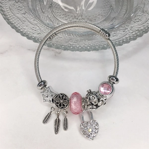 Dettaglio dei ciondoli acchiappasogni e cuore su un bracciale in argento e perle rosa