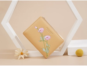 Close-up of beige lychee texture wallet with pink floral embroidery and gold zipper