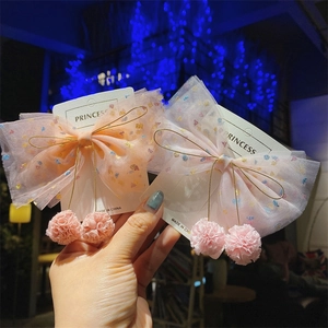 Detail of pink and orange tulle hair clips with sequins and plush ball pendants