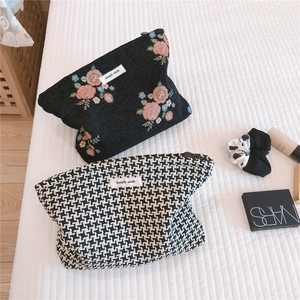 Macro shot of two jacquard cosmetic bags in floral embroidery and houndstooth patterns