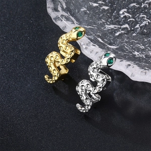 Macro shot of gold and silver snake rings with green gemstone eyes on ice cubes