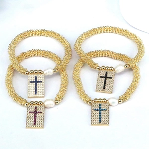 Detail of gold beaded bracelets with zircon cross pendants and natural freshwater pearls