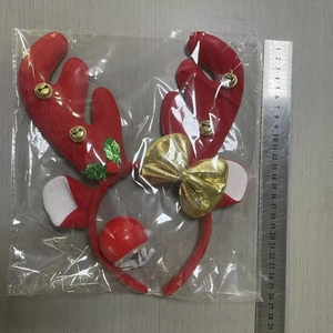 Detail view of a red reindeer antler headband with bells and bow on a wooden surface