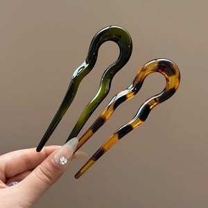 Close-up of elegant acrylic U-shaped hairpins in dark green and amber tortoise shell