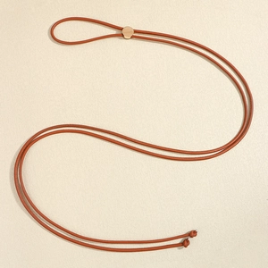 Dettaglio di una cintura in pelle PU marrone con fibbia rotonda dorata e design annodato