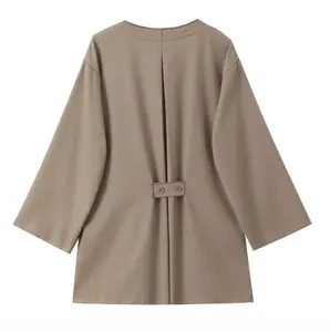 Detail view of khaki long sleeve top featuring vertical back pleats and buttoned strap decor