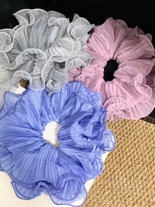 Detailed view of large pleated scrunchies in royal blue, purple and grey chiffon fabrics