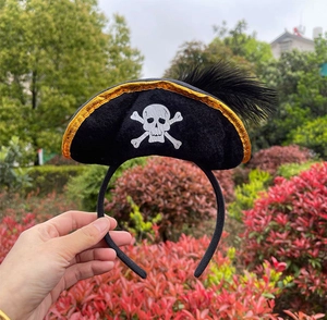 Detail of Halloween pirate hat headband with gold trim, skull logo and black feather