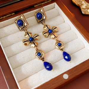 Close-up of vintage gold floral tassel earrings with deep blue gemstones on velvet