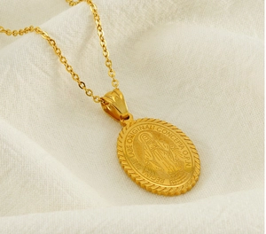 Detail of gold Virgin Mary oval medallion pendant necklace on soft white fabric