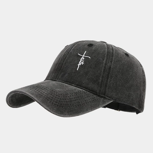 Detail view of the white faith cross embroidery on a washed dark gray baseball cap