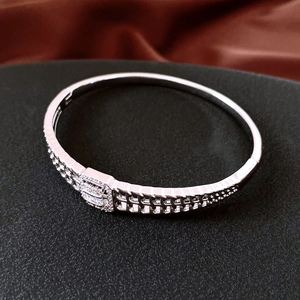Détail d'un bracelet articulé argenté avec texture quadrillée et rectangle incrusté de cristaux