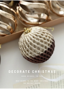Close-up of glittery two-tone Christmas ball with woven texture and gold hanging loop