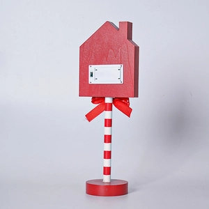 Detail view of the red wooden LED house lamp with a battery box and a festive bow