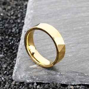 Dettaglio dell'anello in acciaio al tungsteno dorato con tagli geometrici su pietra scura