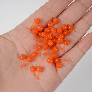 Miniature orange plastic cherry model for DIY crafts and cake decorations held in hand