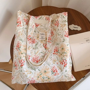 Détail du motif floral et de l'étiquette tissée sur un sac fourre-tout en toile crème
