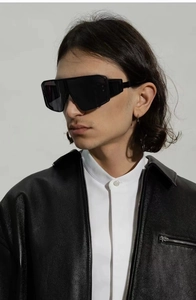 Steampunk oversized black sunglasses worn by male model with dramatic side lighting