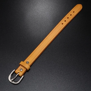 Detail of yellow leather wristband with silver metal buckle and double stitching