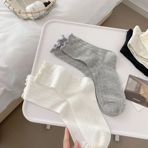 Detail of soft ribbed knit cotton socks with cute ruffled edges in white and grey colors