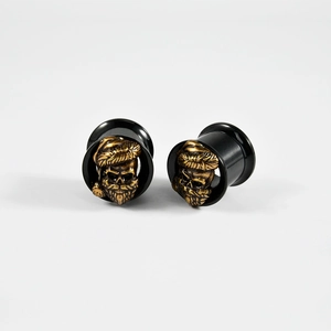 Close-up of black ear gauges with bronze skull wearing a Santa hat detail