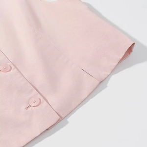 Close-up of pink linen texture and resin button detail on the sleeveless crop top