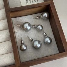 Macro shot of grey pearl earrings on linen lining inside a vintage wooden jewelry box