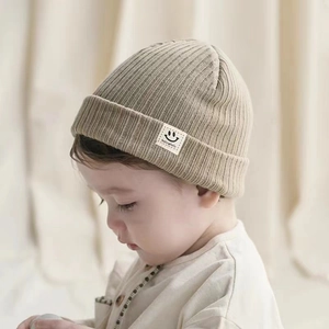 Warm khaki baby knit beanie with a cute smiley face patch and cozy ribbed texture