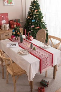 Close-up of red and white Christmas table runner with knitted reindeer and snowflake patterns