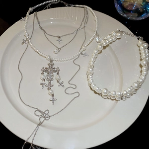 Detail of layered pearl necklace and rhinestone cross pendant on white plate
