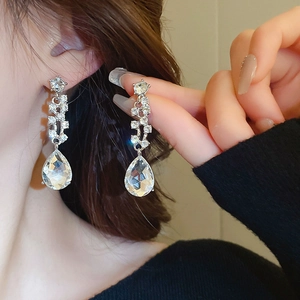 Primo piano di orecchini a goccia in cristallo argento indossati da una modella elegante
