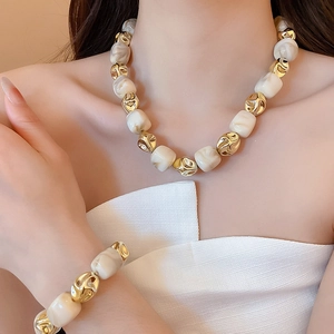 Detailed view of necklace and bracelet set with cream marble beads and gold accents