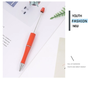Close-up of red retractable metal stylus pen on a modern office desk with greenery