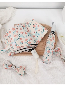 Floral folding umbrella with matching storage pouch and bow accessory on wooden tray