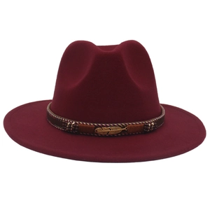 Detail of burgundy fedora hat featuring golden feather pendant and beaded ethnic band