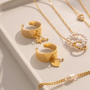 Macro shot of 18K gold plated star and heart jewelry set with pearls on a chic tray