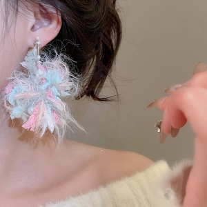Close-up of oversized pink and blue yarn flower earrings with pearl accent on model