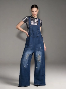 Detail of vintage ripped denim overalls with wide legs and washed texture finish