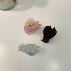Close-up of heart-shaped acetate hair claws in pink, brown and marble white finishes