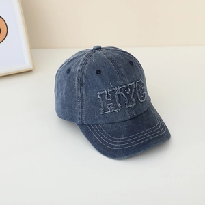 Gros plan de la broderie HYC blanche sur la casquette en denim bleu foncé délavé