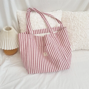 Detail of red and white striped canvas tote bag with decorative label on soft fabric