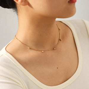 Close-up of a gold stainless steel chain necklace with zircon pendants on a model