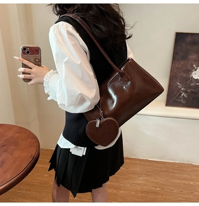 Detail shot of vintage dark brown faux leather tote bag featuring a heart shaped charm