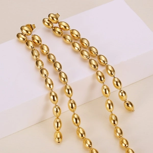 Chic gold-tone titanium steel long tassel drop earrings on white decorative cube