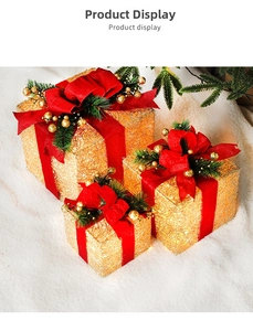 Detail of gold mesh Christmas gift boxes with red velvet bows and warm LED lights