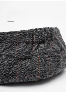 Detail view of the elastic adjustment band on a gray herringbone newsboy cap